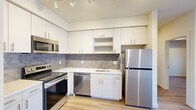 Located at 6121 E Sixth Ave in Spokane Valley, WA, this well-appointed one-bedroom, one-bathroom unit offers a thoughtfully designed layout across a single floor. The open-concept kitchen and living area serves as the heart of the space, where clean lines and modern finishes create a bright, cohesive atmosphere. The kitchen is outfitted with white flat-front cabinetry reaching toward the ceiling, a textured grey tile backsplash, white quartz-style countertops, and a full suite of stainless steel appliances including a refrigerator, range, microwave, and dishwasher. Track lighting illuminates the kitchen, enhancing the sleek, contemporary feel. Light wood-style flooring runs throughout the unit, tying each room together seamlessly. The living area benefits from natural light through a window, offering a comfortable space to relax. The bedroom is a calm, neutral retreat with the same warm flooring, a classic paneled door, and access to a dedicated walk-in closet equipped with wire shelving systems for organized storage. The bathroom features a white vanity with under-cabinet storage, a large mirror with overhead lighting, and a full tub-shower combination, all finished in a clean, minimalist style.