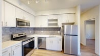 Located at 6121 E Sixth Ave in Spokane Valley, WA, this well-appointed one-bedroom, one-bathroom unit offers a thoughtfully designed layout across a single floor. The open-concept kitchen and living area serves as the heart of the space, where clean lines and modern finishes create a bright, cohesive atmosphere. The kitchen is outfitted with white flat-front cabinetry reaching toward the ceiling, a textured grey tile backsplash, white quartz-style countertops, and a full suite of stainless steel appliances including a refrigerator, range, microwave, and dishwasher. Track lighting illuminates the kitchen, enhancing the sleek, contemporary feel. Light wood-style flooring runs throughout the unit, tying each room together seamlessly. The living area benefits from natural light through a window, offering a comfortable space to relax. The bedroom is a calm, neutral retreat with the same warm flooring, a classic paneled door, and access to a dedicated walk-in closet equipped with wire shelving systems for organized storage. The bathroom features a white vanity with under-cabinet storage, a large mirror with overhead lighting, and a full tub-shower combination, all finished in a clean, minimalist style.