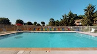 Located at 4121 Kimberly Parkway N in Columbus, Ohio, this single-level property features a well-maintained outdoor pool area that serves as a central recreational amenity. The swimming pool is generously sized, with clear blue water and a marked depth indicator, making it suitable for a range of swimmers. Surrounding the pool is a wide, paved deck lined with colorful Adirondack-style chairs in red, blue, and green, providing ample space for lounging and relaxation. A tall wooden privacy fence encloses the area, offering a sense of seclusion while still allowing views of the surrounding mature trees that create a lush, green backdrop. The open sky above ensures the pool area is bathed in natural sunlight throughout the day, enhancing the overall outdoor experience. The combination of the vibrant seating, well-kept grounds, and natural surroundings gives this outdoor space a welcoming and recreational atmosphere, ideal for warm-weather enjoyment. The layout is practical and accessible, with the single-floor design ensuring ease of movement throughout the property.