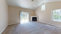 Located at 249 Mill Creek Dr in North Kingstown, Rhode Island, this two-floor home presents a well-organized layout with notable architectural details throughout. The entryway makes an immediate impression with soaring vaulted ceilings, recessed lighting, hardwood flooring, and multiple windows that flood the space with natural light, creating an open and welcoming atmosphere from the moment you step inside.

The main living area continues the vaulted ceiling design and features a corner fireplace with a classic white mantel surround, a ceiling fan, and a sliding glass door that opens directly to the outdoors. The kitchen is equipped with white cabinetry, gray laminate countertops, white appliances including a gas range and dishwasher, and a window above the sink overlooking the exterior.

Bedrooms are carpeted and bright, with vaulted or angled ceilings that add character. One upper-level room showcases a distinctive roofline with angled ceilings, while another benefits from a sliding door with outdoor views. Two bathrooms serve the home — one with a tub-shower combination and one with a standalone shower stall, both finished with neutral tile and clean white fixtures. An attached garage with an automatic opener completes the home.