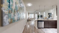 This thoughtfully designed 2-bedroom, 2-bathroom single-story residence offers a comfortable and functional layout with modern finishes throughout. The open-concept entry hallway features wood-look flooring and flows directly into the kitchen and living area, creating a cohesive, connected living space. The kitchen is a standout feature, showcasing dark espresso cabinetry, granite countertops, stainless steel appliances including a refrigerator, microwave, and dishwasher, and a peninsula with bar seating illuminated by sleek pendant lighting and a track light system. The living room is bright and welcoming, benefiting from large windows that invite natural light and provide views of the outdoors. A ceiling fan adds comfort to this relaxed gathering space. Both bedrooms are carpeted and generously sized, with the primary bedroom offering ample room and access to a walk-in closet with dual hanging rods. The bathrooms are well-finished, featuring granite vanity tops, dark cabinetry, wood-look flooring, and a tiled tub and shower combination. Two closets provide substantial storage throughout the residence. The overall ambiance is clean, contemporary, and inviting, with a neutral color palette that enhances the sense of openness and light.
