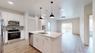Located at 624 North Lancaster Avenue in Dallas, TX, this well-appointed 2-bedroom, 2-bathroom single-story home offers a thoughtfully designed open-concept layout. The modern kitchen serves as the heart of the space, showcasing a central island with a built-in sink, crisp white shaker cabinetry, quartz countertops, a tile backsplash, and a full suite of stainless steel GE appliances including a range, over-the-range microwave, and dishwasher. Stylish pendant lighting illuminates the island, while the kitchen flows seamlessly into the living area, which features wood-look luxury vinyl plank flooring and access to an outdoor balcony through sliding glass doors with vertical blinds. The bedrooms are bright and airy, benefiting from natural light through large windows fitted with blinds and ceiling fans overhead. The primary bedroom connects directly to its own bathroom, which is outfitted with a white vanity, quartz countertop, an LED-lit mirror, and chrome fixtures. Generous walk-in closets with built-in shelving and hanging rods provide ample storage. A dedicated laundry area houses a full-size washer and dryer. The clean, neutral palette and contemporary finishes throughout create a cohesive and inviting atmosphere.