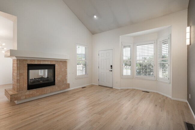 Living Room with Double-Sided Fireplace shared with Dining Room, and Vaulted Ceiling - 7358 E Lowry Blvd