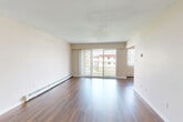 Located at 3851 Francis Rd in Richmond, BC, this well-laid-out two-bedroom, two-bathroom unit offers a comfortable and functional living environment across a single floor. The open living room is a standout feature, showcasing rich hardwood-style flooring, a wall of large sliding glass doors, and vertical blinds that allow for excellent natural light and outdoor views, creating a bright and airy atmosphere. Baseboard heating is present throughout, ensuring year-round comfort. The galley-style kitchen is efficiently designed with white cabinetry extending to the ceiling, granite-look countertops, a stainless steel sink, and white appliances including a range and refrigerator — offering ample storage and prep space. Both bedrooms are generously sized, carpeted for warmth, and feature windows with vertical blinds that bring in natural light. The primary bedroom includes a closet with double doors. The two bathrooms are finished with tile flooring, white vanity cabinetry, granite-look countertops, and large mirrors. In-unit laundry is conveniently accessible from the bathroom area. The unit's neutral warm-toned palette and clean finishes throughout contribute to a cohesive and inviting overall ambiance.