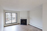 Located at 1174 Hooke Road NW in Edmonton, Alberta, this one-bedroom, one-bathroom unit offers a thoughtfully organized single-floor layout. Light-toned hardwood flooring runs throughout the main living areas, creating a bright, cohesive feel complemented by crisp white walls and textured ceilings.

The living room serves as the focal point of the space, featuring a tile-surround fireplace with a white mantel and a large sliding glass door that opens to a balcony, allowing ample natural light. Adjacent to it, the dining area is illuminated by a classic chandelier, providing a defined space for meals. The kitchen is efficiently designed with white upper and lower cabinetry, a stainless steel sink, white appliances including an electric range and refrigerator, and tile-patterned flooring with a white subway tile backsplash.

The bedroom is a well-proportioned retreat with light hardwood flooring and a full-width sliding-door closet offering generous storage. Additional storage is provided by multiple closets accessible via two hallways. The bathroom features a soaker tub and shower enclosed by elegant marble-style wall tiling, adding a refined touch. The overall layout is practical and efficient, making excellent use of the available floor area.