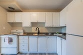 Located at 177 Nonquon Rd in Oshawa, Ontario, this 2-bedroom, 1-bathroom unit offers a well-organized single-floor layout across a comfortable footprint. The entry hallway, equipped with an intercom panel, leads into the open living area, which features warm parquet wood flooring and a textured ceiling that carries throughout much of the space. The living room is a standout area, highlighted by large floor-to-ceiling sliding glass doors that open to a balcony, flooding the room with natural light and offering pleasant views of the surrounding greenery and neighbourhood. The kitchen is positioned adjacent to the living area and includes white cabinetry, a white electric range, a refrigerator, dark granite-style countertops, and durable vinyl flooring. Both bedrooms are well-proportioned, benefiting from large windows that bring in generous amounts of natural light. The primary bedroom features a double bi-fold closet for ample storage. The bathroom is clean and functional, appointed with a white vanity, under-mount sink, and a mirrored medicine cabinet. Neutral tones and consistent parquet flooring throughout the living and bedroom areas create a cohesive and practical living environment.