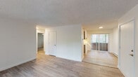Located at 19705 SW Boones Ferry Rd in Tualatin, Oregon, this single-floor unit offers a clean, well-maintained layout with a bright and neutral aesthetic throughout. The open living and dining areas are finished with light wood-style laminate flooring that extends through the main spaces, complemented by textured ceilings and crisp white walls that enhance the sense of openness. Large windows dressed with vertical blinds allow generous natural light to filter in while offering views of the surrounding greenery. Baseboard heating is present throughout, providing efficient warmth across the unit. The kitchen features grey cabinetry, white countertops, a stainless steel refrigerator, and sliding panel doors that conceal additional storage, making it both functional and tidy. The bedroom is carpeted for comfort and includes a ceiling fan, a wide sliding-door closet, and a window framing lush outdoor tree views. The bathroom is outfitted with a full tub-shower combination, a curved shower rod, wood-style tile flooring, and a vanity with ample counter space. The overall layout is practical and efficiently organized, offering a comfortable living environment in a well-connected Tualatin location.