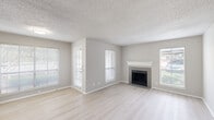Located at 2439 Spanish Trail in Arlington, Texas, this single-story home presents a clean, updated interior with a cohesive neutral color palette and light wood-style flooring carried throughout. The living area serves as the centerpiece of the layout, featuring a tile-surround fireplace with a white mantel and multiple windows fitted with blinds that invite generous natural light. The open feel of the space is complemented by textured popcorn ceilings and soft gray walls.

The kitchen is thoughtfully designed with gray shaker-style cabinetry, a white countertop peninsula with an integrated sink, stainless steel appliances including a refrigerator, range, and microwave, and a subway tile backsplash. The peninsula connects the kitchen visually to the main living area, supporting an open-concept flow.

The bedrooms are well-proportioned, each featuring light wood-style flooring, ceiling fans, and access to closet storage. Windows provide natural light and views of the surrounding area. The bathroom includes a full tub and shower combination with a clean white surround and chrome fixtures. Overall, the home presents a bright, updated, and functional living environment.