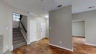 Located at 4439 Rainier St in Irving, TX, this two-story home combines functional design with comfortable living across multiple well-appointed spaces. The main living area makes an immediate impression with rich, dark hardwood-style flooring, neutral gray walls, and a ceiling fan overhead. A standout granite-surround fireplace with a raised hearth serves as the room's focal point, while a sliding glass door allows natural light to fill the space. The open entryway features the same hardwood-style flooring and provides direct access to a staircase leading to the upper level. The kitchen is well-equipped with dark espresso cabinetry, granite-look countertops, a mosaic tile backsplash, black appliances including a range, built-in microwave, and dishwasher, along with a double-basin sink beneath a window. The bathrooms include a full bath with a tub-shower combo and wood-look flooring, as well as a bath featuring an extended granite vanity countertop with a large mirror and Hollywood-style lighting. The bedrooms are finished with plush carpet and feature generous walk-in closets with built-in shelving. Textured ceilings are consistent throughout, adding a classic architectural detail to every room in the home.