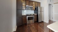 Located on Granby Street in the heart of Norfolk, Virginia, this single-floor residence offers a well-designed layout that balances comfort and functionality. Rich, dark-stained hardwood flooring flows consistently throughout the living areas and bedrooms, lending warmth and a polished aesthetic to every room.

The living spaces are bright and open, benefiting from multiple windows dressed with horizontal blinds that filter natural light throughout the day. Ceiling fans are present in the bedroom areas, contributing to year-round comfort. Clean white walls and crisp baseboards create a neutral backdrop that complements the deep wood tones underfoot.

The kitchen is a standout feature, outfitted with dark espresso-toned cabinetry reaching toward the ceiling, light stone countertops, and a classic subway tile backsplash. Stainless steel appliances—including a range, microwave, and refrigerator—give the kitchen a contemporary, functional character. An island provides additional prep space and contributes to an open flow between the kitchen and living areas. An in-unit washer and dryer adds everyday convenience.

The bathroom is finished with large-format, neutral-toned tile on both the floor and tub surround, creating a clean and serene atmosphere. Overall, the space presents a cohesive, modern aesthetic with quality finishes throughout.