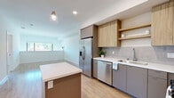 Located at 4949 Baltimore Drive in La Mesa, California, this contemporary two-story home offers four bedrooms and two bathrooms across a well-distributed layout spanning two floors. The design emphasizes clean lines, neutral tones, and light wood-style flooring throughout, creating a bright and cohesive aesthetic.

The main floor centers around an open-plan kitchen and living area. The modern kitchen is equipped with stainless steel appliances — including a French door refrigerator, gas range, microwave, and dishwasher — complemented by two-tone cabinetry featuring warm wood uppers and sleek grey lowers, white quartz countertops, a tile backsplash, and a kitchen island with pendant lighting. A dramatic floor-to-ceiling black-framed window wall floods the living area with abundant natural light and frames views of the surrounding neighborhood.

The two bathrooms are finished in a clean, contemporary style — one features a walk-in shower with white tile surround, while the other includes a full soaking tub and shower combo. The four bedrooms are bright and well-proportioned, with large windows inviting natural light. The primary bedroom provides a comfortable and private retreat. Staircases connect both floors, and the consistent use of light wood flooring and crisp white walls throughout gives the entire home a fresh, move-in-ready feel.