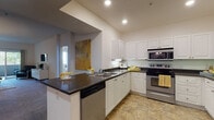 Located at 9800 Mira Lee Way in San Diego's Mira Mesa community, this single-floor residence offers a thoughtfully designed layout with a clean, contemporary aesthetic throughout. The kitchen is a standout feature, equipped with stainless steel appliances including a refrigerator, range, and built-in microwave, complemented by white shaker cabinetry, dark countertops, and tile flooring. A breakfast bar with seating extends from the kitchen, creating a seamless transition into the living and dining areas. The dining space is anchored by an elegant chandelier and connects conveniently to an in-unit laundry area. The spacious living room features soft carpeting, vaulted ceilings, and sliding glass doors that open to a private balcony, filling the room with natural light and outdoor views. The bedrooms are carpeted and generously sized, each offering ceiling fans, natural light from windows, and ample closet storage. The bathrooms are finished with tile flooring, white vanity cabinetry, dark countertops, and tub-shower combinations. A consistent warm, neutral color palette with accent tones of yellow and grey runs throughout the home, creating a cohesive and welcoming ambiance across all rooms.