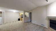 This single-floor residential unit offers a functional and well-organized layout designed for comfortable everyday living. The spacious living area is finished with plush carpeting and features vaulted ceilings that lend an open, airy feel to the space. A sliding glass door provides access to an outdoor balcony, allowing natural light to fill the room. The semi-open kitchen is connected to the living area via a pass-through opening and is equipped with light wood cabinetry, stainless steel appliances including a refrigerator, range, microwave, and dishwasher, along with light-toned countertops and tile flooring. The bedrooms are generously sized, each with soft carpeting, neutral-toned walls, and windows fitted with blinds that offer natural light and outdoor views. One bedroom includes direct access to a full bathroom, enhancing privacy and convenience. The bathrooms feature tile flooring, wood vanities with stone-look countertops, large mirrors, and chrome fixtures. A second carpeted room with darker flooring provides flexible use as an additional bedroom or private retreat. Throughout the unit, a consistent neutral color palette and clean finishes create a calm, cohesive ambiance.