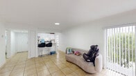 Located in Hialeah, FL, this single-floor unit offers a well-organized layout across one bedroom and three bathrooms. The open-plan living area is bright and airy, featuring large light-toned ceramic tile flooring that runs throughout the entire space, clean white walls, and recessed lighting that enhances the sense of openness. A sliding glass door with vertical blinds in the living room allows natural light to flow in freely.

The kitchen is efficiently designed with white cabinetry, marble-look countertops, stainless steel appliances including a full-size refrigerator and range, and a peninsula with bar seating — making it both functional and inviting. The layout allows the kitchen to open naturally toward the living area, promoting an easy flow between spaces.

The spacious primary bedroom is a comfortable retreat with clean white walls, tile flooring, and ample room for furnishings. A dedicated closet adds practical storage. The hallway connects the rooms smoothly and leads to the bathrooms, which are finished with tile flooring, vanities with stone-look countertops, and a tub-shower combination in one. The crisp, neutral palette throughout gives the entire unit a clean, cohesive feel.