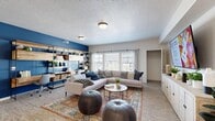 Located at 8933 S Cobblegate Dr in Sandy, UT, this well-appointed 2-bedroom, 2-bathroom single-floor home offers a thoughtfully designed open-concept layout. The combined kitchen and living area serves as the heart of the home, featuring light wood-look flooring, a bold navy blue accent wall, and an industrial-style built-in shelving unit that doubles as a workspace. Large windows flood the living room with natural light and offer views of the surrounding neighborhood. The kitchen is equipped with stainless steel appliances, white shaker cabinets, dark granite countertops, a tile backsplash, and a dedicated dining area. The spacious primary bedroom features a striking blue half-wall accent, plush carpet, a ceiling fan, and a double-door closet providing ample storage. The second bedroom is equally comfortable with its own closet. Both bathrooms are finished with wood-look tile flooring, white vanity cabinets, and dark countertops — one featuring a tub/shower combo and the other a clean, minimalist vanity with a round mirror. A hallway connects the private sleeping quarters to the main living areas, completing this cohesive and modern floor plan.