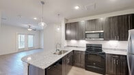 Located at 4909 E Lancaster Ave in Fort Worth, Texas, this single-story, three-bedroom, two-bathroom home offers a well-designed layout with modern finishes throughout. Light wood-style flooring runs continuously across the home, creating a cohesive and clean aesthetic in every room.

The kitchen is a standout feature, showcasing dark wood cabinetry with sleek hardware, granite-style countertops, a stainless steel refrigerator, built-in microwave, and a black electric range. A large kitchen island with an undermount sink and pendant lighting above adds both function and style, while under-cabinet lighting enhances the workspace.

The three bedrooms are bright and comfortable, each equipped with ceiling fans. Several bedrooms feature windows that allow natural light to fill the space, and one bedroom benefits from additional transom-style windows positioned high on the wall for extra brightness. Three closets provide ample storage, including a walk-in closet with built-in shelving.

The bathrooms are well-appointed; one features a dual-sink vanity with granite countertops, a soaking tub, and a separate glass-enclosed walk-in shower with white subway tile. The clean, neutral palette and modern fixtures throughout lend the home a fresh, contemporary feel.