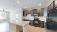 Located at 5375 Allatoona Gateway in Acworth, GA, this single-floor, three-bedroom, two-bathroom home offers a thoughtfully designed layout with modern finishes throughout. The kitchen serves as a central highlight, showcasing rich dark cabinetry, light granite countertops, a full suite of black appliances including a refrigerator, range, and built-in microwave, and a peninsula island that provides additional prep space and casual seating. Light wood-style flooring runs through the kitchen and main areas, lending warmth and a clean aesthetic. The two bathrooms maintain a consistent style with dark vanity cabinetry, light stone countertops, and wood-look flooring. One bathroom features a full tub-shower combo with brushed nickel fixtures, while the other offers a more compact layout. The three bedrooms are carpeted for comfort and feature neutral toned walls that create a calm, versatile backdrop. Select bedrooms include ceiling fans and broad windows with blinds, allowing ample natural light and views of surrounding greenery. Two closets provide practical storage throughout the home. The overall design is clean and contemporary, with a cohesive color palette of soft neutrals, dark accents, and light finishes that give the space a polished, move-in-ready feel.