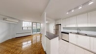 Located at 28 Helene St N, Unit 403 in Mississauga, this well-designed one-bedroom, one-bathroom residence offers a comfortable and functional layout across a single floor. The open-concept kitchen and living area form the heart of the unit, with the kitchen featuring crisp white shaker-style cabinetry extending to the ceiling, dark countertops, a subway tile backsplash, gleaming tile flooring, and a full suite of stainless steel appliances including a refrigerator, dishwasher, stove, and microwave. A central island provides additional prep and dining space. The living room is bathed in natural light from large windows and sliding balcony doors, showcasing beautifully polished parquet wood flooring that extends throughout the main living areas and bedroom. A wall-mounted air conditioning unit ensures year-round comfort. The bedroom is a well-proportioned retreat featuring mirrored sliding closet doors and a bright window with outdoor views. The bathroom is finished with classic white subway tile surrounding a full soaker tub and shower combination. Step outside onto the private balcony to enjoy open views of the surrounding Mississauga streetscape and skyline. A hallway connects all areas of the unit seamlessly, completing this thoughtfully laid-out home.
