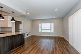 Located along The Paseo Blvd in Kansas City, MO, this single-story unit offers a thoughtfully designed layout with contemporary finishes throughout. The open-concept living and dining area is anchored by rich, dark hardwood-style flooring that extends seamlessly throughout the main living spaces. Multiple windows dressed with blinds invite natural light, creating a bright and welcoming atmosphere, while recessed lighting and stylish pendant lights over the kitchen island add warmth and dimension.

The kitchen is well-appointed with a full suite of stainless steel appliances, including a refrigerator, range, microwave, and dishwasher. Granite countertops span both the island and perimeter counters, complemented by a two-tone cabinet design featuring dark lower cabinets and crisp white upper cabinets with a classic subway tile backsplash.

The primary bathroom features a dual-sink vanity with granite countertops, dark wood cabinetry, and a walk-in tiled shower. A secondary bathroom offers a single vanity with matching finishes and a tiled shower. Bedrooms are carpeted for comfort and include mirrored sliding closet doors. The overall aesthetic is clean, modern, and move-in ready.