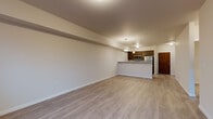 Located at 1403 South Assembly Street in Spokane, WA, this thoughtfully designed unit offers a clean, contemporary aesthetic throughout its single-floor layout. The open-concept living and dining area is anchored by light-toned luxury vinyl plank flooring, neutral walls, and abundant natural light streaming in through a glass exterior door that leads to a private balcony with views of surrounding evergreen trees. Pendant lighting over the kitchen peninsula adds a warm, modern touch to the space. The galley-style kitchen is well-appointed with rich dark-stained cabinetry, crisp white quartz countertops, stainless steel appliances including a refrigerator, range, microwave, and dishwasher, and a single-basin undermount sink. The bedroom is carpeted for comfort, features a generously sized window framing peaceful wooded views, and connects to a well-organized bathroom complete with dark cabinetry, quartz countertops, and an open wire-shelf closet system for ample storage. A dedicated laundry area houses a full-size top-loading washer and dryer. Additional storage is provided by a spacious walk-in closet near the entry. The unit presents a neutral, move-in-ready palette ideal for a variety of living styles.