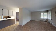 Located at 21 58th St in Clarendon Hills, Illinois, this single-floor residence offers a well-organized layout designed for comfortable everyday living. The expansive living area is carpeted and filled with natural light streaming through multiple large windows fitted with blinds, offering views of the surrounding neighborhood. Baseboard heating runs throughout the main living spaces, ensuring warmth during cooler months. A wall-mounted air conditioning unit provides additional climate control in the main room. The entry foyer opens directly into the bright and generously proportioned living space, which connects seamlessly to the kitchen area. The kitchen is thoughtfully appointed with two-tone cabinetry — white upper cabinets paired with gray lower cabinets — set against a classic white subway tile backsplash and light countertops. A stainless steel gas range and a double-basin sink with a window above add both function and character. Wood-look flooring grounds the kitchen and bathroom. The bedroom is a comfortable, carpeted retreat featuring a built-in closet with shelving and a rod for organization, along with direct access to additional areas of the unit. The full bathroom is clean and bright, featuring a tiled tub-shower combination and wood-look vinyl flooring, completing this practical and move-in-ready residence.