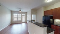 This well-appointed 2-bedroom, 2-bathroom residence in Houston, TX (77070) is thoughtfully designed across a single floor with a practical and inviting open-concept layout. The living and dining area features rich hardwood-style flooring, a ceiling fan, and large windows with blinds that allow generous natural light to fill the space. A sliding glass door provides additional brightness and outdoor access.

The kitchen is positioned adjacent to the living area and is equipped with warm cherry wood cabinetry extending to the ceiling, dark granite countertops, a tiled backsplash, and a full suite of black appliances including a refrigerator with ice maker, electric range, and over-the-range microwave. A peninsula with matching granite countertop offers additional workspace and separation between the kitchen and living areas.

Both bedrooms feature plush neutral carpet, ceiling fans, and windows with blinds that bring in natural light. Each room offers a calm, comfortable atmosphere with ample wall space.

The two bathrooms are finished with light ceramic tile flooring. The primary bathroom includes a double-sink vanity with warm wood cabinetry, a large mirror with Hollywood-style lighting, and a soaking tub with shower. The secondary bathroom features a tub-shower combination with white tile surround and recessed lighting. Both bathrooms maintain a clean, functional aesthetic throughout.