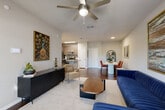 Located at 9835 Namaste Loop in Orlando, FL, this well-appointed one-bedroom, one-bathroom residence offers a thoughtfully designed single-floor layout. The open-concept living, dining, and kitchen area serves as the heart of the home, featuring rich hardwood-style flooring, recessed lighting, and a ceiling fan. The kitchen is outfitted with stainless steel appliances, granite countertops, a mosaic tile backsplash, taupe cabinetry, and a large granite-topped island with bar seating — ideal for both cooking and entertaining. A dedicated dining area provides additional space for meals. The bedroom is generously sized with plush carpet, natural light from multiple windows, a ceiling fan, and two closets for ample storage. The bathroom includes granite countertops, a wide vanity, and quality finishes. Additional practical spaces include a pantry, laundry room, and utility room. A private balcony extends the living space outdoors, offering open views of lush palm trees and the surrounding community. The overall ambiance is modern and comfortable, blending functional design with contemporary finishes throughout.