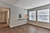 This single-story residence on Jasmine Pkwy in Roswell, Georgia, offers a thoughtfully updated interior with a neutral color palette throughout. The main living area features wood-look flooring and vaulted ceilings with recessed lighting, creating an open and airy atmosphere that adapts well to various furniture arrangements.

The kitchen is outfitted with two-tone cabinetry—crisp white uppers paired with gray lowers—complemented by white quartz countertops, a stainless steel sink with a modern pull-down faucet, a tile backsplash, and stainless steel appliances including an electric range and over-the-range microwave. A window above the sink allows natural light into the space.

Multiple bedrooms are finished with plush carpeting, neutral gray walls, and ceiling fans or flush-mount light fixtures. Several rooms feature corner window configurations fitted with blinds, bringing in ample natural light and views of the surrounding greenery.

The bathrooms feature wood-look vinyl flooring, dark gray vanity cabinetry, white countertops, and brushed nickel hardware. One bathroom includes a tub-shower combination, while another presents a more compact layout. The clean, consistent finishes across the home create a cohesive and move-in-ready environment.
