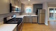 This single-floor unit offers a thoughtfully designed layout with a clean, contemporary aesthetic evident in every room. The open living area is anchored by warm hardwood-style flooring and neutral gray walls, with recessed lighting overhead and a sliding glass door that connects the interior to an outdoor deck, allowing natural light to flow freely into the space.

The kitchen is a standout feature, outfitted with gray shaker-style cabinetry, white quartz countertops, and a textured tile backsplash. A full suite of stainless steel appliances — including a gas range, built-in microwave, dishwasher, and refrigerator — completes the well-equipped cooking space. A pendant light above the sink and a window overlooking the exterior add brightness and character.

The bedrooms are finished with plush neutral carpet and feature generous closet space, including a mirrored sliding-door closet in one room. Each bedroom benefits from natural light through well-placed windows.

The bathroom is finished with floor-to-ceiling tile, a gray vanity with an undermount sink and stone-look countertop, and a soaking tub enclosed by a frameless sliding glass panel. Chrome fixtures and a frosted window complete the polished, spa-like feel.