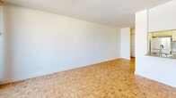 Located on the 8th floor at 2021 Avenue Atwater in Montréal's vibrant Shaughnessy Village neighbourhood, this compact studio unit offers a well-organized and efficiently designed living space. The interior is finished with classic light wood parquet flooring in a basket-weave pattern throughout, lending warmth and character to the clean, white-walled interior.

The open living area is the heart of the unit, benefiting from generous natural light through a large floor-to-ceiling sliding glass door that opens onto a private balcony. Vertical blinds provide light control, while the balcony offers elevated views of the surrounding Montréal cityscape. A built-in kitchen area is neatly integrated along one wall, featuring counter space and room for essential appliances, maintaining an open and uncluttered feel.

A hallway entrance leads from the front door into the living space, offering a natural transition into the unit. The full bathroom is finished in crisp white subway tile surrounding a soaking bathtub and shower combination, complemented by a taupe-toned countertop, overhead cabinetry, and a mirrored medicine cabinet — maximizing both storage and functionality within the compact space.

Overall, the unit presents a clean, minimalist aesthetic with a bright and airy ambiance, well-suited for urban living in a central Montréal location.