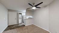 This single-floor residence offers a practical and well-appointed layout with a neutral color palette and textured ceilings throughout. The open living area is a central feature, anchored by a tile-surround fireplace and built-in shelving that adds both storage and visual interest. A ceiling fan with integrated lighting keeps the space comfortable, while a sliding glass door fitted with vertical blinds provides access to an outdoor area and allows natural light to filter in. Plush carpeting extends throughout the living and sleeping areas, contributing to a warm ambiance.

The kitchen is efficiently designed in a galley configuration, featuring white cabinetry, light stone countertops, stainless steel appliances including a refrigerator, electric range, microwave, and dishwasher, along with wood-look flooring and a walk-in pantry for ample storage. A pass-through counter connects the kitchen to the living space. An in-unit stacked washer and dryer is conveniently located nearby.

Two bathrooms serve the residence. One includes a soaking tub and shower combination with tiled surround and a window for natural light. The second features a separate glass-door shower, an extended vanity with white cabinetry, and wood-look tile flooring. The bedrooms are carpeted and bright, with windows providing outdoor views.
