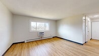 This 2-bedroom, 1-bathroom unit at 303 27th St SW in Austin, MN offers a clean, updated interior with a practical and efficient layout. Light wood laminate flooring runs consistently throughout the space, complemented by neutral gray walls, dark baseboards, and textured ceilings that add subtle character. The living room is a bright, open area with a large sliding window that invites natural light and provides views of the surrounding trees and neighborhood. A wall-mounted air conditioning unit and baseboard heating ensure year-round comfort. The kitchen features white cabinetry with black hardware, light stone-look countertops, and a full suite of stainless steel appliances including a refrigerator, electric range, and over-the-range microwave, all set on matching wood-look flooring. Both bedrooms are comfortably sized with natural light from sliding windows, baseboard heating, and closet storage — the primary bedroom includes a double-door closet. The full bathroom is finished with a clean white tub and shower surround with built-in shelving and chrome fixtures. The unit presents a move-in ready space with modern updates throughout.
