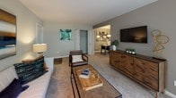 This single-floor residence offers a thoughtfully designed layout that balances comfort and functionality across its key living spaces. The living room serves as the heart of the home, featuring plush carpeting, neutral tones, and floor-to-ceiling sliding glass doors that open to a private balcony overlooking lush, tree-lined greenery — filling the space with abundant natural light. Adjacent to the living room, a dedicated dining area provides an intimate setting accented by a statement pendant light.

The galley-style kitchen is efficiently designed with rich, warm-toned cabinetry, granite countertops, hardwood-style flooring, and a full suite of stainless steel appliances, including a gas range, microwave, refrigerator, and dishwasher. It connects seamlessly to the dining area for easy entertaining.

The primary bedroom is generously proportioned with soft carpeting and direct access to an en-suite bathroom and a walk-in closet. The en-suite features tile flooring, a white vanity with cabinet storage, a mirrored medicine cabinet, and a shower-tub combination. A second bedroom, equally well-lit with a large window, shares access to a second full bathroom via a carpeted hallway. Both bedrooms offer a calm, restful ambiance with ample natural light.