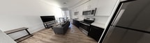 This 360 square foot apartment in Sacramento, CA, exemplifies efficient urban living with its thoughtful design and modern amenities. The space comprises one bedroom, one bathroom, and an open-concept living area with a kitchen. The bathroom features a sleek design with a dark wood vanity, white countertop, and a spacious shower with white subway tile. The kitchen is a highlight, boasting a contemporary aesthetic with contrasting white upper and dark lower cabinets, stainless steel appliances, and a stylish backsplash. Wood-look flooring throughout adds warmth and continuity. The bedroom, while compact at 80 square feet, includes a desk area for work or study. Large windows in the living area provide natural light, enhancing the sense of space. The apartment's layout maximizes functionality in its limited square footage, making it an ideal option for those seeking a modern, low-maintenance living space in an urban setting.