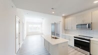 Located at 87 Federal City Rd in Lawrence Township, NJ, this two-story home offers a thoughtfully designed layout across two floors. The main level is generously proportioned, housing the primary living areas, kitchen, and the majority of the home's square footage. Light-toned luxury vinyl plank flooring runs throughout, complementing the clean, neutral color palette.

The kitchen is a standout feature, showcasing light gray shaker-style cabinetry, a classic subway tile backsplash, stainless steel appliances, and a central island with a built-in sink — ideal for both cooking and casual dining. A barn-style sliding door leads to an in-unit stacked washer and dryer area, adding practical convenience.

The bedrooms feature vaulted ceilings and windows that invite natural light, creating bright, airy retreats. The primary bedroom is spacious and includes a well-organized walk-in closet with built-in shelving and double hanging rods. The upper floor offers an additional room with a wall-mounted mini-split HVAC unit.

The two bathrooms are finished with clean, modern fixtures. One features a glass-enclosed walk-in shower with wood-look tile surround, while the other includes a full soaking tub with tiled surround. Hallways and closets round out the efficient and functional floor plan, making this a well-appointed home in a convenient New Jersey location.