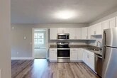 Located at 1229 Tulip St in Liverpool, NY, this single-floor, 2-bedroom, 2-bathroom unit offers a clean, modern aesthetic throughout. The kitchen serves as a functional centerpiece, featuring crisp white shaker-style cabinetry, granite countertops, stainless steel appliances including a range, built-in microwave, dishwasher, and refrigerator, all set atop durable hardwood-style flooring that extends through the common areas. The open layout connects the kitchen seamlessly to the living area, creating an efficient and welcoming flow.

The spacious primary bedroom is generously sized, featuring soft carpeting, a ceiling fan, and multiple windows that invite abundant natural light while offering views of the surrounding neighborhood. The second bedroom also features plush carpeting and ample space. With four closets throughout the unit, storage is well-addressed.

Both bathrooms are finished with white cabinetry, granite-topped vanities, and hardwood-style flooring, maintaining a consistent, polished look. Baseboard heating is present throughout, ensuring comfort year-round. The overall palette of soft grays, whites, and warm wood tones lends the unit a bright, neutral, and move-in-ready ambiance, ideal for those seeking modern, low-maintenance living in Liverpool, NY.