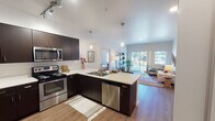 Located at 12623 Bridgeport Way SW in Lakewood, Washington, this single-floor residence offers a thoughtfully designed open-concept layout that promotes a seamless flow between the kitchen, dining, and living areas. The kitchen is a functional centerpiece, featuring dark espresso cabinetry, light quartz countertops, stainless steel appliances including a range, microwave, and dishwasher, and a peninsula with bar seating. Track lighting and pendant fixtures illuminate the space effectively. Wood-style flooring extends throughout the main living areas, adding warmth and continuity.

The living room is bright and inviting, benefiting from large sliding glass doors that open to a private balcony, allowing generous natural light and outdoor views to enhance the interior ambiance. A secondary window further contributes to the well-lit atmosphere.

The unit includes two bedrooms, both carpeted and comfortably sized, each featuring closets and windows that bring in natural light. The two bathrooms are finished with light tile flooring, white soaking tub-shower combinations, and dark vanity cabinetry with white countertops, maintaining a clean and cohesive aesthetic consistent with the rest of the home.