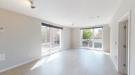 Located at 4115 NE Martin Luther King Jr Blvd in Portland's vibrant NE neighborhood, this single-floor unit showcases a clean, contemporary design with an open and airy feel. Light-toned hardwood-style flooring runs throughout, complementing the neutral, warm wall tones and crisp white trim that define the interior palette.

The main living area is a standout, featuring multiple oversized windows and sliding glass doors fitted with sleek roller shades. These expansive glazed openings flood the space with natural light while offering direct views of the surrounding urban streetscape and mature trees. A second living or flex area also benefits from large windows and a sliding glass door, further enhancing the sense of openness.

The kitchen is finished with contemporary wood-grain cabinetry, white quartz countertops, a subway tile backsplash, and stainless steel appliances including a gas range, built-in microwave, and dishwasher. Bedroom spaces are well-proportioned, offering sliding closet doors and walk-in closet access. The bathroom features a full tub-shower combination with clean tile surrounds and light flooring. Throughout the unit, recessed lighting and track fixtures provide ample illumination, rounding out a thoughtfully designed, modern living environment.