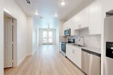 This thoughtfully designed one-bedroom, one-bathroom unit in Austin, TX offers a clean, modern aesthetic throughout. Light-toned luxury vinyl plank flooring flows seamlessly across the entire space, complementing the bright white walls and recessed lighting that keep the interior feeling open and airy.

The kitchen is well-appointed with a full suite of stainless steel appliances, including a range, microwave, dishwasher, and a side-by-side refrigerator with ice and water dispenser. White shaker-style cabinetry with brushed nickel hardware provides ample storage, while granite countertops and a classic subway tile backsplash add a polished finish. The kitchen opens directly into the living area, creating a practical and connected layout.

The living area is anchored by French doors that open to a private balcony, offering natural light and outdoor views. A ceiling fan keeps the space comfortable year-round.

The bedroom is a calm, well-lit retreat featuring a ceiling fan, a window with blinds for natural light and privacy, and access to a dedicated closet.

The bathroom features a full tub-shower combination with floor-to-ceiling warm-toned tile, a toilet, and built-in shelving for added storage. The overall design throughout the unit is clean, contemporary, and move-in ready.