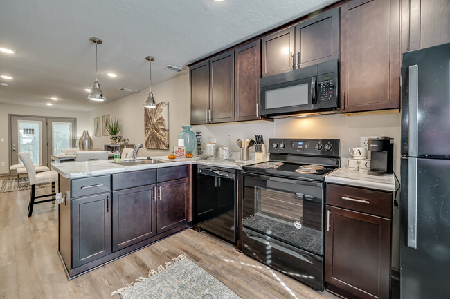 Kitchen with cherry wood cabinets and black appliances - Forest Hills Racquet Club