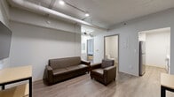 Located in the heart of downtown Denver at 1401 Curtis St, this 2-bedroom, 2-bathroom unit offers a compact yet functional layout with a distinct industrial-modern character. Throughout the space, light wood-tone flooring provides a warm contrast to the crisp white walls and exposed overhead ductwork, lending an urban loft aesthetic.

The living room serves as the central gathering area, furnished with seating and a wall-mounted television, with recessed lighting and visible ductwork overhead contributing to the industrial feel. Adjacent to the living area, the galley-style kitchen is well-appointed with white cabinetry, clean white countertops, a tiled backsplash, and stainless steel appliances, making efficient use of the available space.

Both bedrooms are thoughtfully laid out and feature light wood flooring and natural wood-accented doors. The primary bedroom benefits from large windows offering elevated views of the Denver skyline, flooding the room with natural light. The second bedroom also includes a window with city views and wardrobe storage.

Each bathroom is straightforward and clean in design, featuring a stand-up shower, toilet, and wood-toned flooring that ties into the overall aesthetic. The unit's location in downtown Denver provides convenient access to the city's core amenities and cultural destinations.