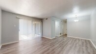 This single-floor residence offers a clean, neutral aesthetic throughout, with light gray walls and white trim providing a cohesive backdrop across all rooms. The living area is a generous, open space finished with light-toned luxury vinyl plank flooring that runs seamlessly through much of the unit. A full wall of vertical blinds covers a large sliding glass door, allowing abundant natural light to filter in while providing direct access to an outdoor patio area. A dedicated entryway with its own exterior door offers a welcoming transition into the living space.

The galley-style kitchen is efficiently laid out with white cabinetry lining both sides, offering ample storage above and below the countertops. White appliances — including an electric range, refrigerator, and dishwasher — are neatly integrated alongside a double-basin sink. The LVP flooring continues here, contributing to easy maintenance.

The bedroom is carpeted in a neutral tan tone and features a ceiling fan with a light fixture, along with double closet doors providing generous storage. The bathroom includes a full tub and shower combination with diagonal tile surround, LVP flooring, and classic white fixtures. The overall layout is practical and well-organized.
