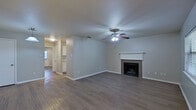 This single-floor, one-bedroom, two-bathroom residence is thoughtfully designed to maximize its compact footprint. The living room serves as the focal point of the unit, featuring a classic wood-mantled fireplace with a tile surround, a ceiling fan with integrated lighting, and wood-look flooring that extends throughout the space. Natural light enters through windows fitted with blinds, lending a bright and open feel. A front entry door with sidelight window provides additional illumination.

The kitchen is efficiently laid out with white cabinetry, light countertops, a dishwasher, and a window that brings in natural light. A pendant light fixture highlights the kitchen area, which connects conveniently to the main living spaces.

The primary bedroom is a comfortable, well-proportioned room featuring a ceiling fan, dark wood-look flooring, and direct access to one of two full bathrooms. That bathroom includes a tub-shower combination, a single-sink vanity with white cabinetry, and a lighted mirror. A dedicated closet provides additional storage.

The second full bathroom mirrors a similar clean, functional aesthetic. Throughout the unit, neutral gray walls, consistent flooring, and white trim create a cohesive and modern ambiance.
