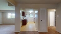 Located at 736 Camberley Circle in Towson, Maryland, this single-floor residence offers a well-organized layout designed for comfortable everyday living. The kitchen is accessed through a wide archway from the main living area and features rich wood cabinetry, granite-style countertops, light hardwood flooring, a white electric range with overhead microwave, and a refrigerator. Multiple windows allow natural light to flow through the space, creating a bright and functional cooking environment. Adjacent to the kitchen is a dedicated laundry area equipped with a stacked washer and dryer unit, complemented by additional cabinetry and a utility sink with matching countertop. The generously sized living area is finished with plush wall-to-wall carpeting and includes a pendant light fixture, providing a warm and open atmosphere. Bedrooms are carpeted and well-lit by wide windows that offer views of surrounding greenery. One bedroom features an impressive three-section closet wall, providing abundant built-in storage with shelving and hanging rods. The bathroom includes wood vanity cabinetry, a wide mirror, mosaic tile flooring, and tile-clad walls, offering a clean and classic finish. Overall, the space presents a practical and comfortable single-level living environment in a residential Towson neighborhood.