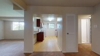 Located at 736 Camberley Circle in Towson, Maryland, this single-floor residence offers a well-organized layout designed for comfortable everyday living. The kitchen is accessed through a wide archway from the main living area and features rich wood cabinetry, granite-style countertops, light hardwood flooring, a white electric range with overhead microwave, and a refrigerator. Multiple windows allow natural light to flow through the space, creating a bright and functional cooking environment. Adjacent to the kitchen is a dedicated laundry area equipped with a stacked washer and dryer unit, complemented by additional cabinetry and a utility sink with matching countertop. The generously sized living area is finished with plush wall-to-wall carpeting and includes a pendant light fixture, providing a warm and open atmosphere. Bedrooms are carpeted and well-lit by wide windows that offer views of surrounding greenery. One bedroom features an impressive three-section closet wall, providing abundant built-in storage with shelving and hanging rods. The bathroom includes wood vanity cabinetry, a wide mirror, mosaic tile flooring, and tile-clad walls, offering a clean and classic finish. Overall, the space presents a practical and comfortable single-level living environment in a residential Towson neighborhood.