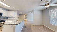 Located at 3555 Austell Rd in Marietta, Georgia, this single-floor unit offers a well-designed, open-concept layout that seamlessly connects the kitchen, dining, and living areas. The kitchen is a standout feature, appointed with crisp white shaker cabinetry, light granite countertops, a subway tile backsplash, stainless steel appliances including a gas range, built-in microwave, and refrigerator, and a peninsula with an integrated sink that overlooks the main living space. Durable hardwood-style flooring runs through the kitchen, transitioning to soft, neutral carpeting throughout the living and bedroom areas. The living space is generously proportioned, with a ceiling fan and sliding glass doors that open to a private balcony, allowing for natural light and outdoor access. The bedroom is well-sized with a window providing natural light, and a textured ceiling is consistent throughout the home. Additional rooms offer closet storage with clean white panel doors. The bathroom features a full soaking tub and shower combination with brushed nickel fixtures and wood-style flooring. Neutral gray walls and a light color palette give the entire space a clean, move-in-ready feel.