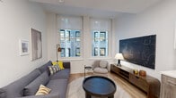Located in the heart of Philadelphia at 130 S Juniper Street, Unit 508, this thoughtfully designed one-bedroom, one-bathroom residence makes excellent use of its compact footprint. Light wood flooring flows throughout, tying together the open-plan layout and lending a warm, contemporary feel.

The combined kitchen and living area serves as the heart of the unit. The living space features two large windows that frame city views, flooding the room with natural light. The kitchen is outfitted with stainless steel appliances, dual-tone cabinetry pairing white uppers with wood-finish lowers, white quartz countertops, a subway tile backsplash, and a central island with seating — ideal for casual dining or entertaining.

The bedroom accommodates a full-sized bed and offers its own window with city views, providing natural light and a comfortable atmosphere. Glass-paneled doors and a closet with louvered doors add refined, functional detail to the space.

The bathroom is finished with large-format tile flooring, a wood-finish vanity topped with a white quartz surface, a warm wood-framed mirror, and a tiled shower, creating a clean and spa-like environment.

A hallway with a rich wood-paneled entry door connects the rooms, completing this efficient and stylish urban residence.