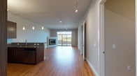 This well-designed single-floor residence offers a thoughtfully planned open-concept layout finished with warm hardwood flooring that flows throughout the main living areas. The living and dining space is generously proportioned, anchored by a corner fireplace and bathed in natural light from large sliding glass doors that open directly to a paved outdoor patio — ideal for seamless indoor-outdoor living. Track lighting runs the length of the ceiling, complementing the clean, contemporary aesthetic.

The kitchen is a standout feature, equipped with stainless steel appliances including a gas range, microwave, refrigerator, and wine cooler. Rich walnut-toned cabinetry pairs elegantly with granite countertops and a subway tile backsplash, offering both style and functionality. A kitchen island with pendant lighting provides additional prep space and casual seating.

The bedrooms are comfortable and well-lit, featuring plush carpeting, ceiling fans, and windows with outdoor views. The bathrooms are finished to a high standard, showcasing granite-topped walnut vanities, large-format tile flooring, and a glass-enclosed walk-in shower in the primary bath.

A dedicated utility room houses the washer, dryer, water heater, and HVAC system, keeping all mechanical elements organized and out of the way. The overall ambiance is modern, clean, and move-in ready.