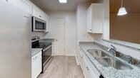 This single-floor residence at 3349 Glade Creek Blvd NE in Roanoke, Virginia offers a well-organized layout with a clean, neutral aesthetic throughout. The living area is bright and open, featuring warm hardwood-style flooring and French doors that introduce natural light while providing access to the outdoors. A peninsula with pendant lighting visually connects the living space to the kitchen, creating an airy, open-concept feel.

The kitchen is thoughtfully equipped with white shaker-style cabinetry, granite countertops, stainless steel appliances including a refrigerator with ice maker, electric range, and microwave, along with a skylight that fills the space with additional natural light. A separate door within the kitchen leads to additional storage or utility access.

The bedrooms feature plush carpeting, ceiling fans, natural light from windows, and closet space. Two full bathrooms are present, each featuring a tub-shower combination with curved curtain rods and wood-style flooring, finished in neutral tones.

A dedicated laundry area accommodates a full-size washer and dryer alongside a water heater, with overhead wire shelving for added storage. Throughout the unit, white trim, neutral walls, and consistent flooring choices contribute to a cohesive and move-in-ready atmosphere.
