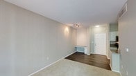 This single-floor unit at 8465 Regents offers a clean, well-maintained interior characterized by a thoughtful blend of materials and finishes. The main living area features plush, neutral-toned carpeting that transitions seamlessly into dark hardwood-style flooring near the entryway, creating a natural delineation between spaces. Walls are finished in a soft, warm neutral tone that lends the space a bright and welcoming ambiance, complemented by clean white baseboards and trim throughout.

A notable built-in desk with a drawer is positioned along the wall near the entry, offering a practical workspace or organizational station without occupying additional floor space. The entryway is framed by a classic paneled white door and benefits from overhead lighting that provides a well-lit welcome area.

Track lighting is mounted on the ceiling of the main area, allowing for adjustable, directed illumination throughout the room. The smooth white ceiling and consistent lighting enhance the sense of openness. Overall, the unit presents a tidy, move-in-ready environment with functional built-in features and a cohesive neutral palette suited to a variety of furnishing styles.